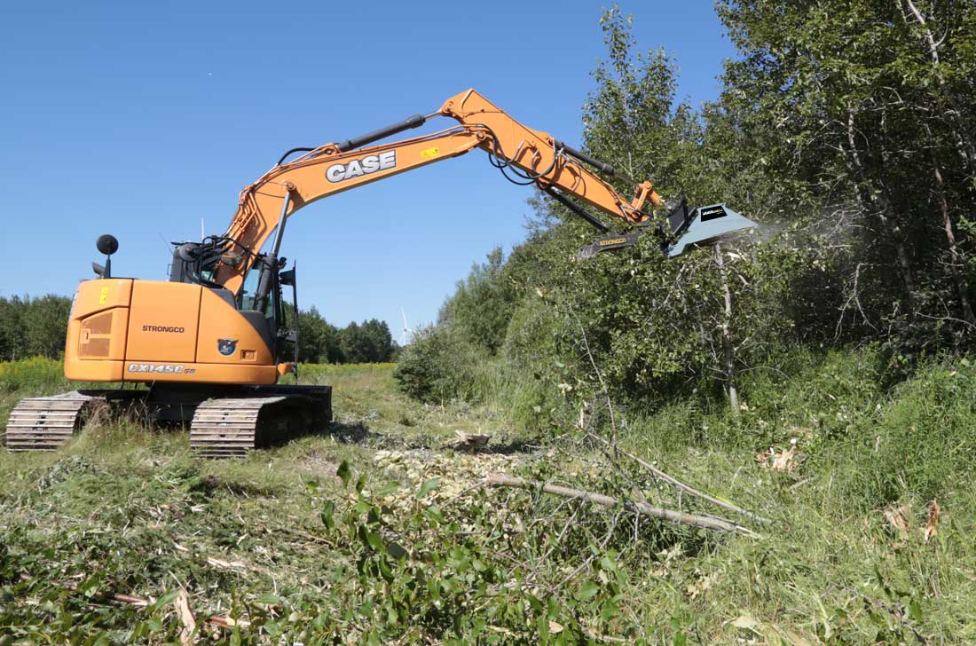 Excavator carrying a Baumalight CXC550 brush cutter beside a cleared area