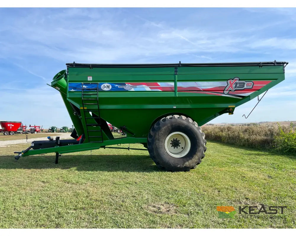 Side profile of a green J&M 1312 wheeled grain cart at Keast Enterprises