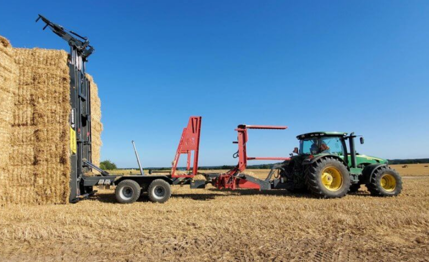 Anderson StackPro 7200 beside an upright stack of square bales after unloading