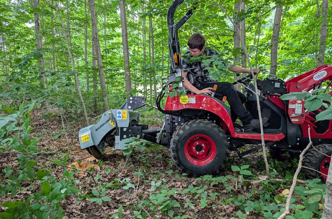 Side view of the Baumalight 1P14 stump grinder mounted behind a red subcompact tractor