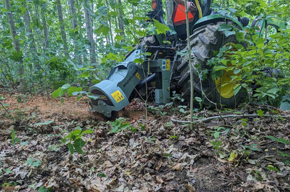 Baumalight 1P14 cutting head working behind a green tractor in woodland