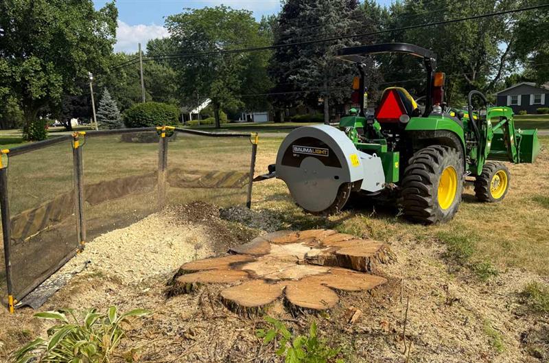 Baumalight 1P34 stump grinder raised behind a tractor beside a large stump