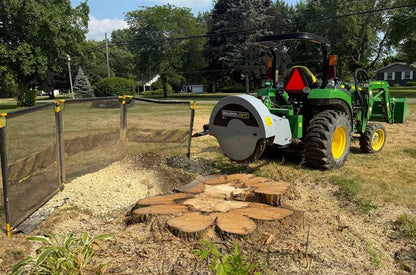 Baumalight 1P34 stump grinder raised behind a tractor beside a large stump