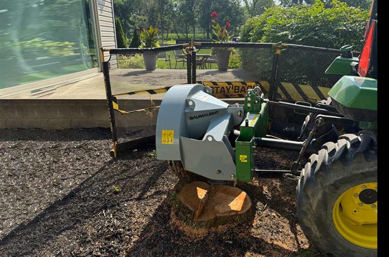 Opposite-side view of the Baumalight 1P34 stump grinder working behind a tractor