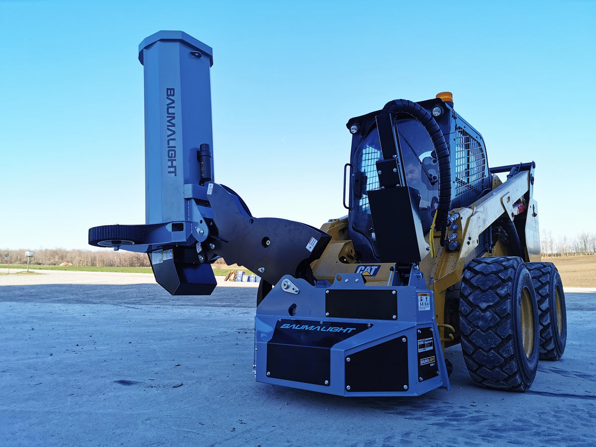 Baumalight SWA550 boom mower with the flail head raised vertically beside a skid steer
